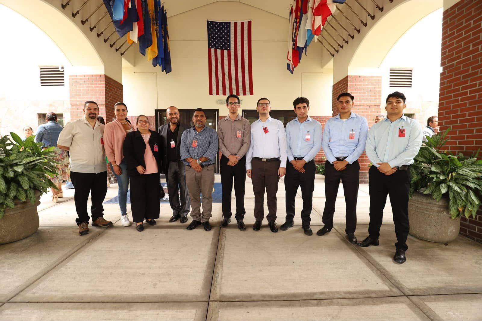 Delegación de la Universidad de Sonsonate frente a un edificio con banderas internacionales durante una visita en el extranjero